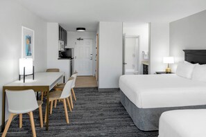 A hotel room with a bed, a desk with chairs, a kitchenette, and a bathroom. - TownePlace Suites Marriott Joplin (Joplin)