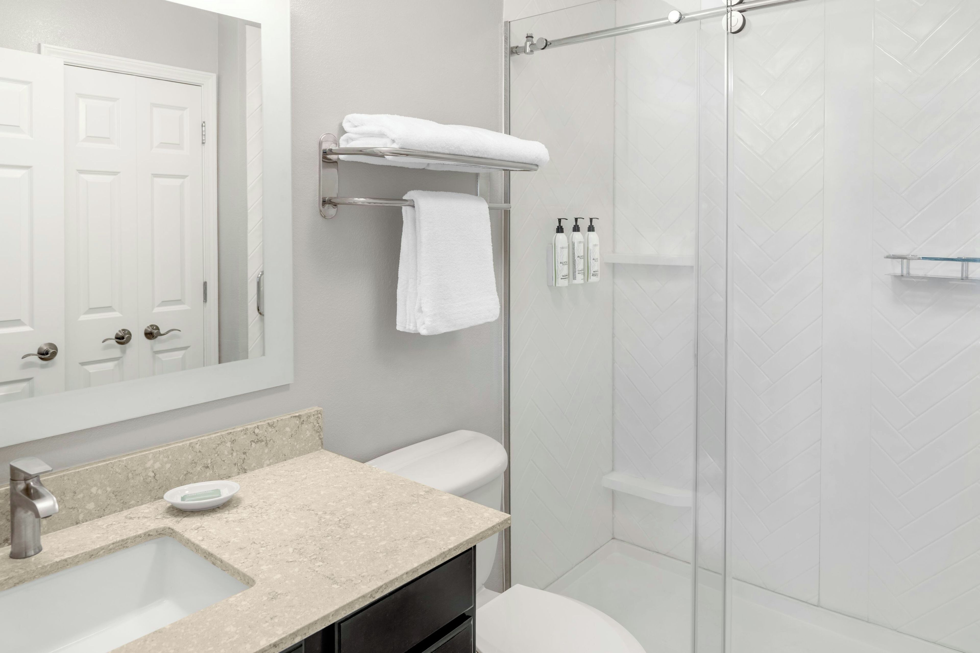 A bathroom with a sink, mirror, toilet, and shower.