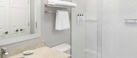 A bathroom with a sink, mirror, toilet, and shower.