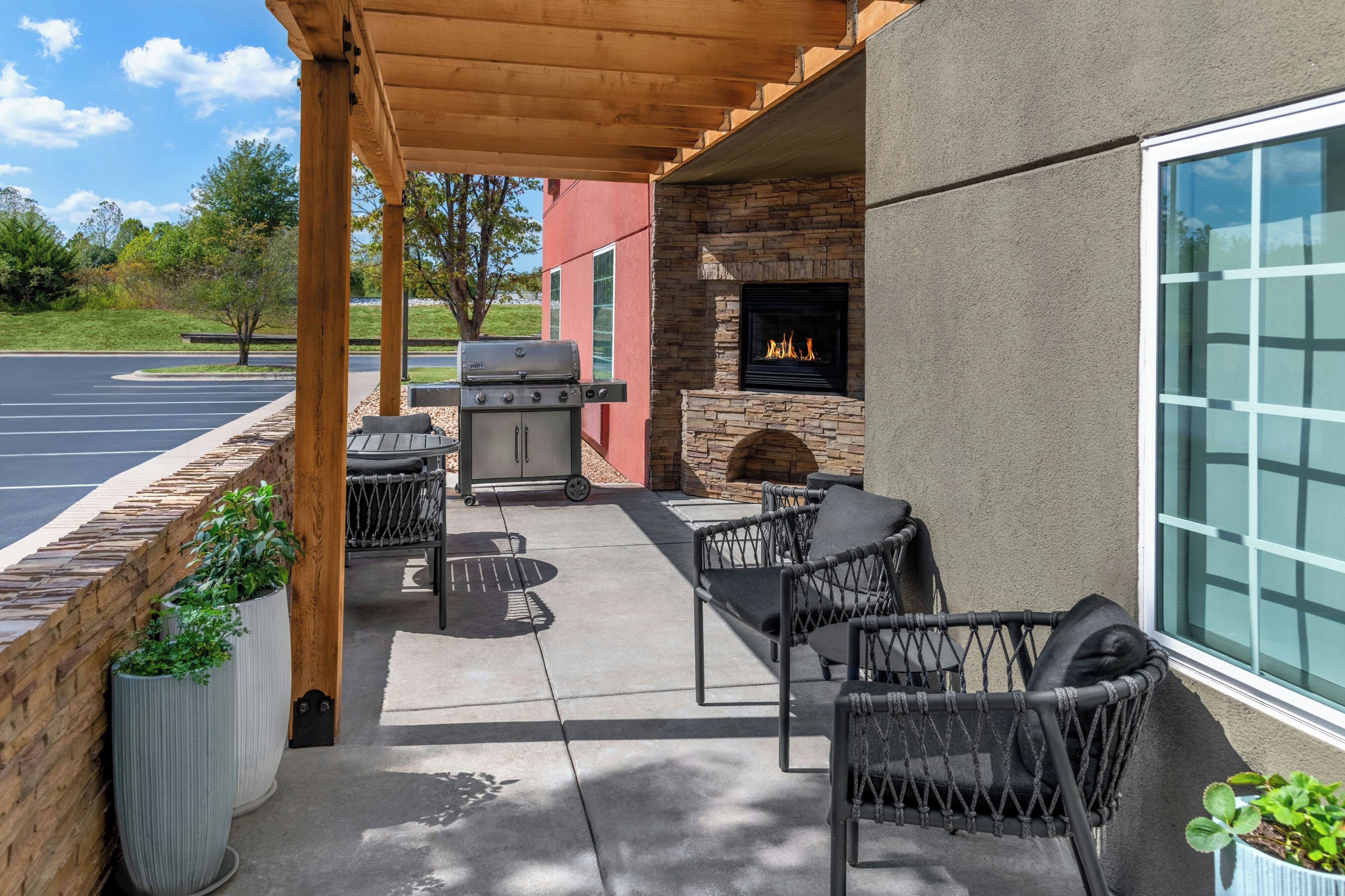 An outdoor patio with a grill, seating, and a stone fireplace.
