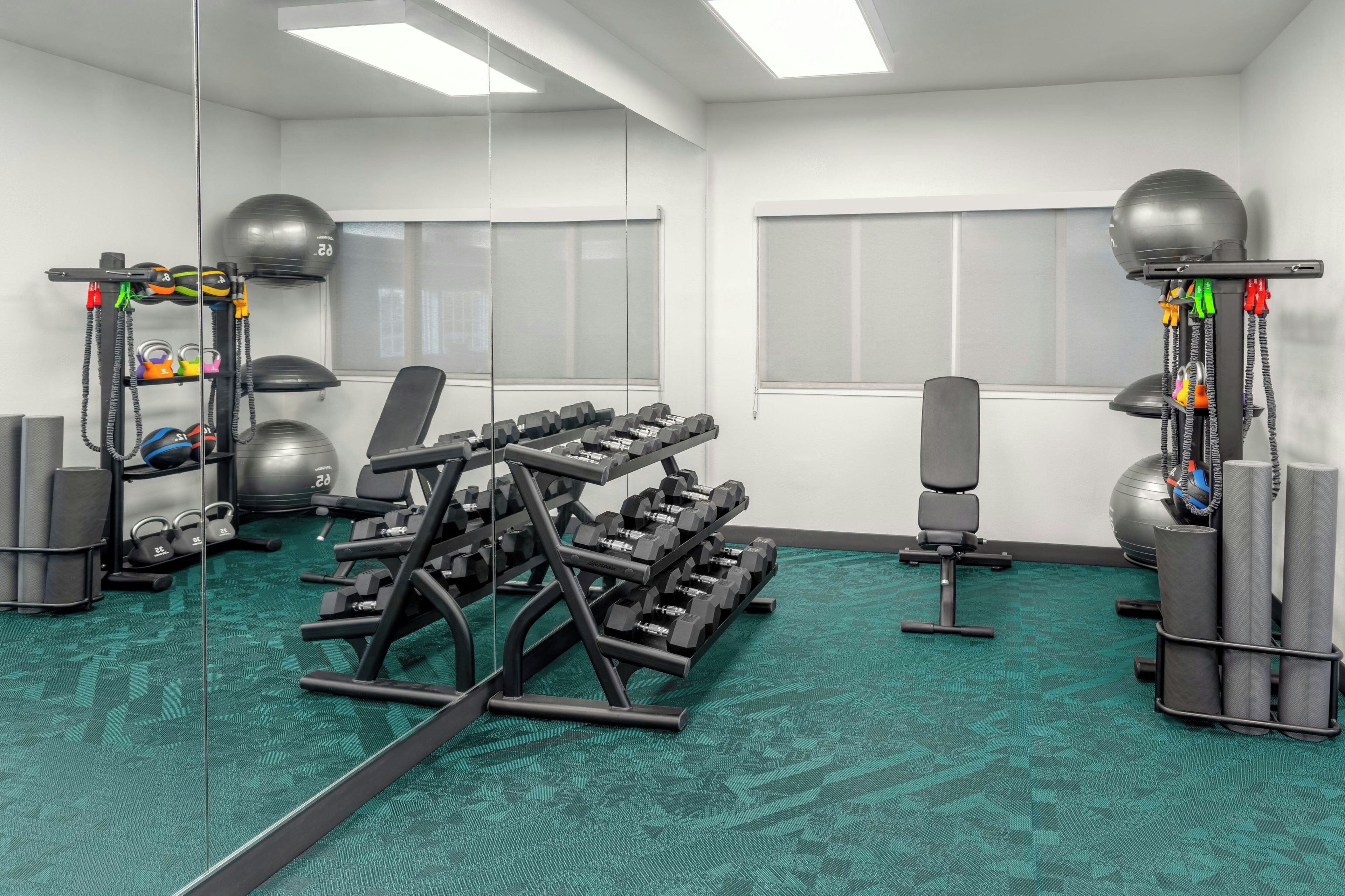 Un gimnasio con equipo de ejercicio, un espejo y una alfombra verde.