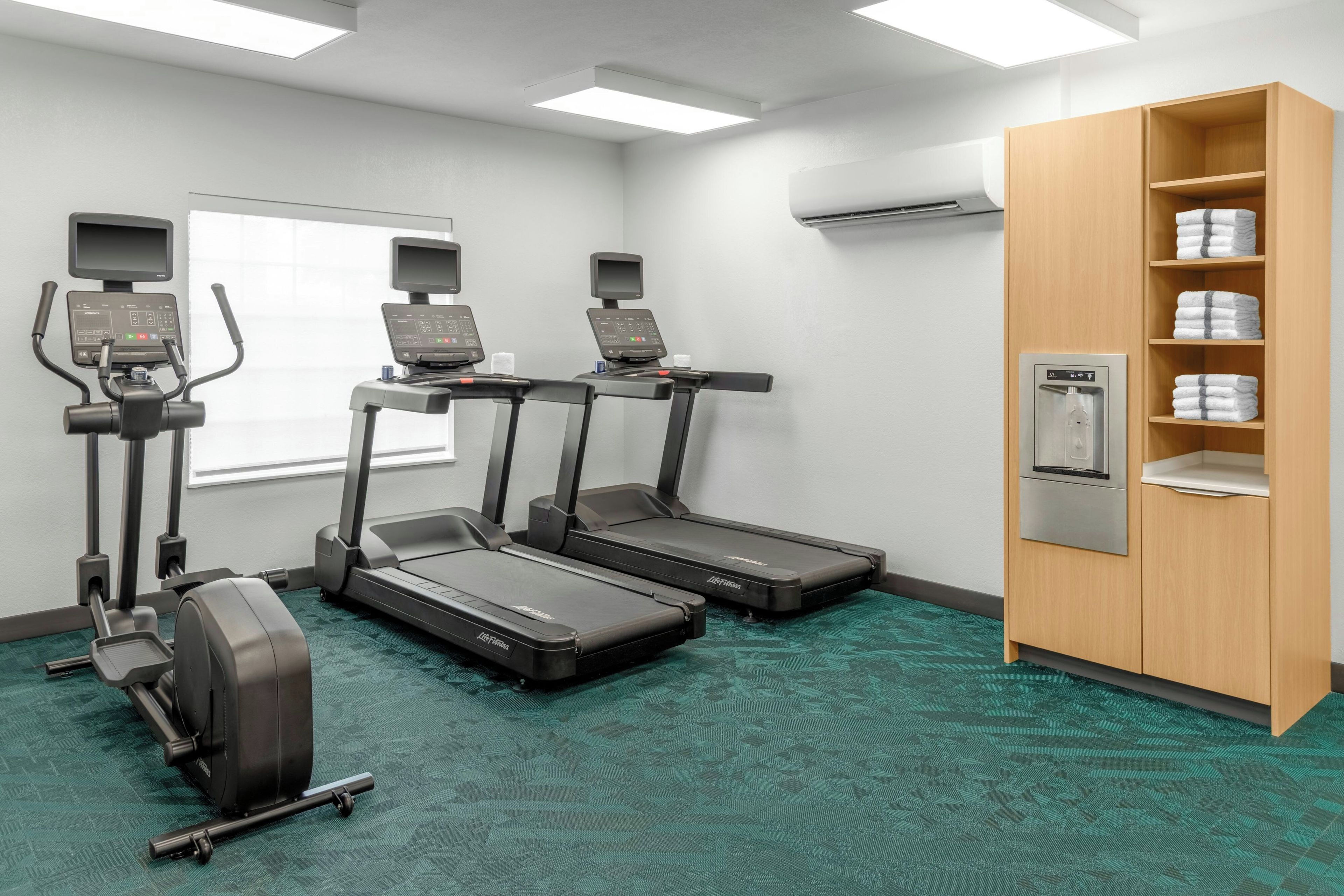 A fitness room with treadmills, a stationary bike, and a water dispenser.