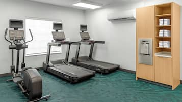 A fitness room with treadmills, a stationary bike, and a water dispenser.