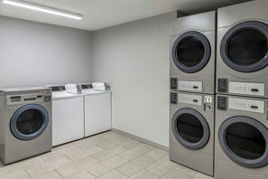 A laundry room with four front-loading washing machines and a dryer. - TownePlace Suites Marriott Joplin (Joplin)