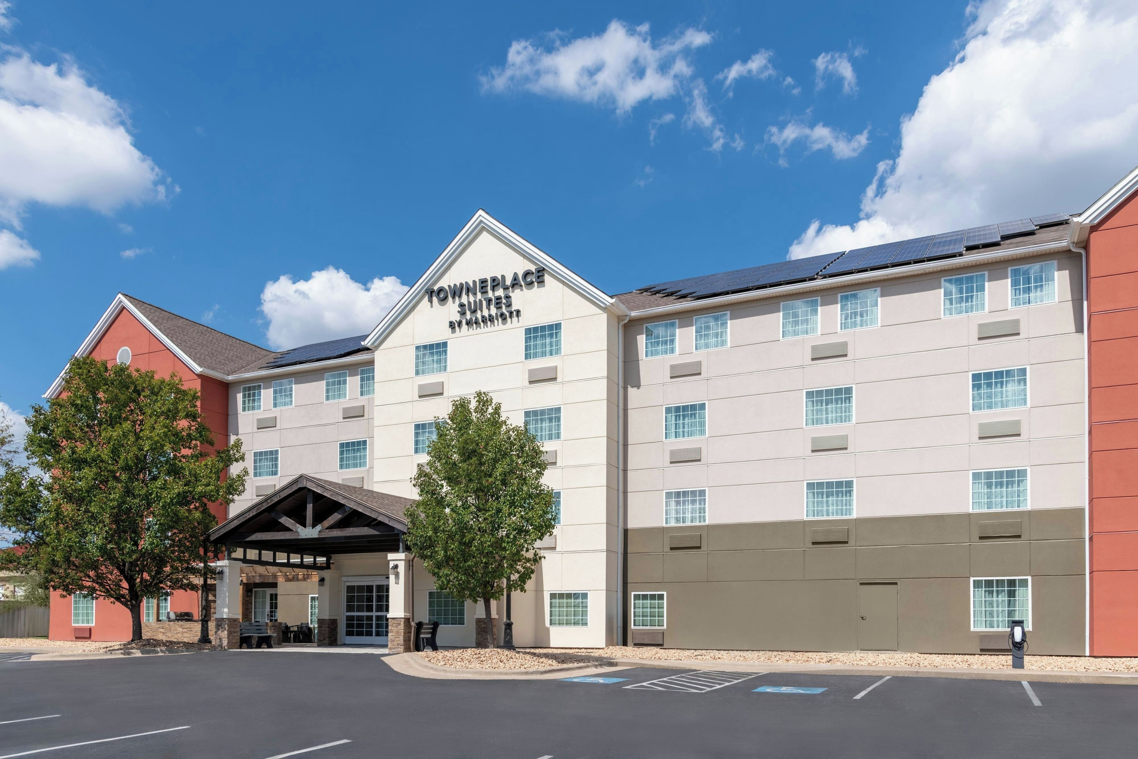Un hotel con un cartel visible que dice 'TOWNEPLACE SUITES BY MARRIOTT' y un estacionamiento con plazas reservadas para discapacitados.
