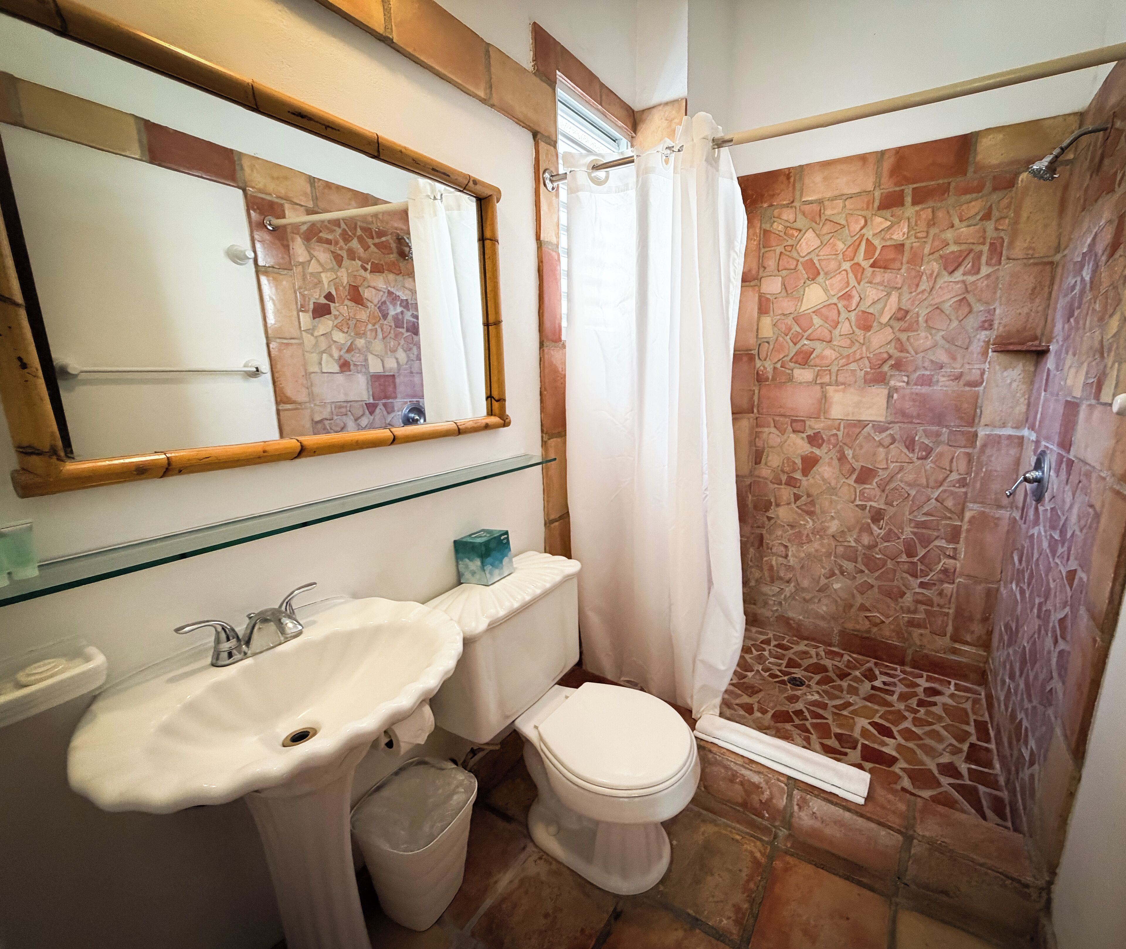 Een badkamer met een witte wastafel, toilet en douche.