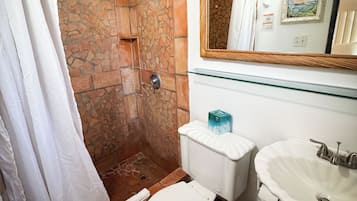 Un baño con ducha, inodoro, lavabo y espejo.
