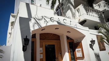 Exterior de l'Hotel Acacia Boutique, amb una entrada arqueada destacada, portes de fusta i un rètol sobre l'entrada.
