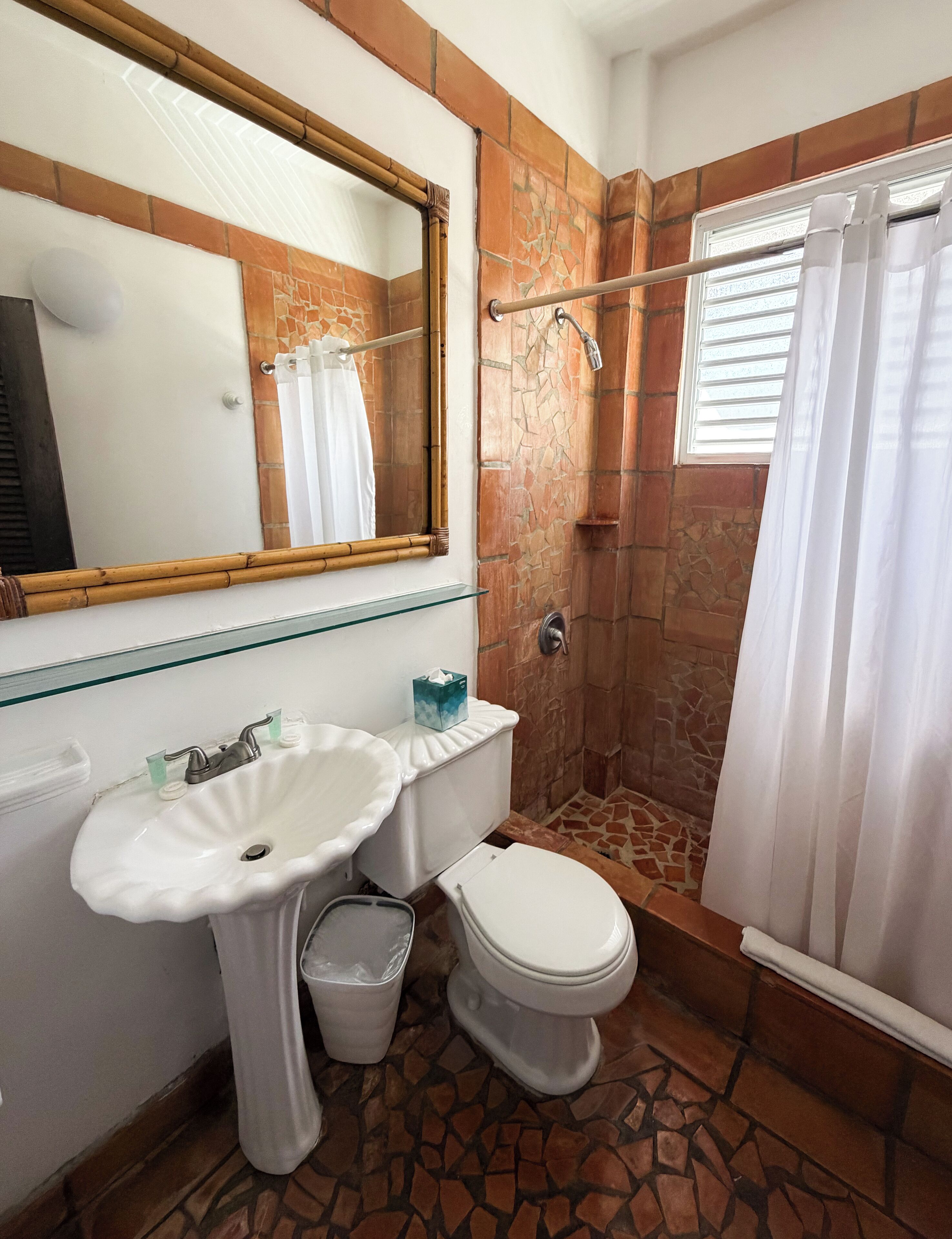 A bathroom with a white sink, a toilet, a shower with a glass door, and a large mirror.