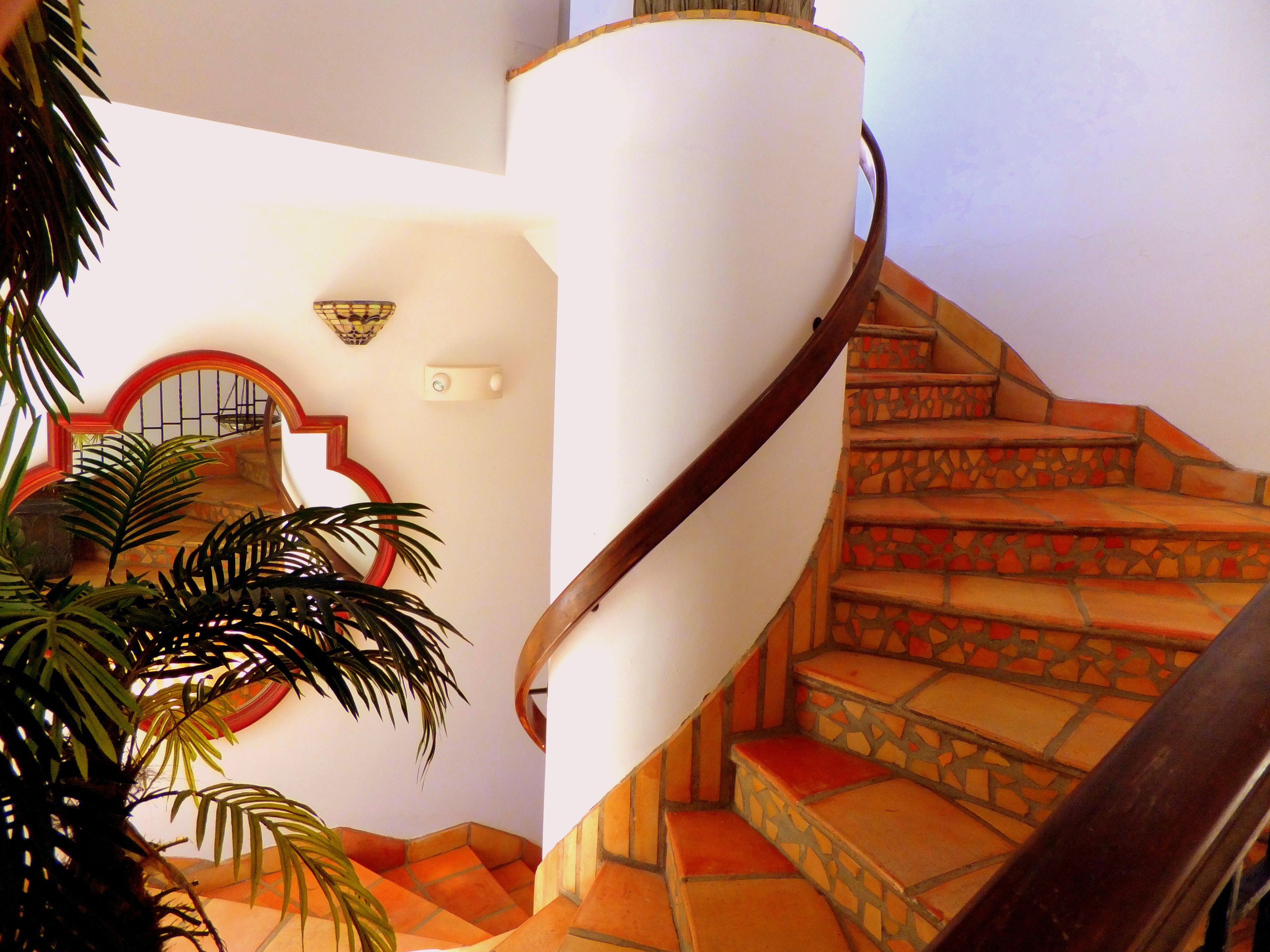 Una escalera de caracol con una pared blanca y un espejo con marco rojo.