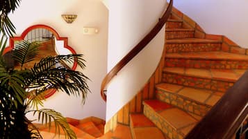 Una escalera de caracol con una pared blanca y un espejo con marco rojo.