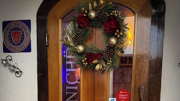 Une porte à double battant en bois, ornée d’une guirlande festive, d’une enseigne « Diners Choice » et d’une plaque « Château de Rotisseurs ».