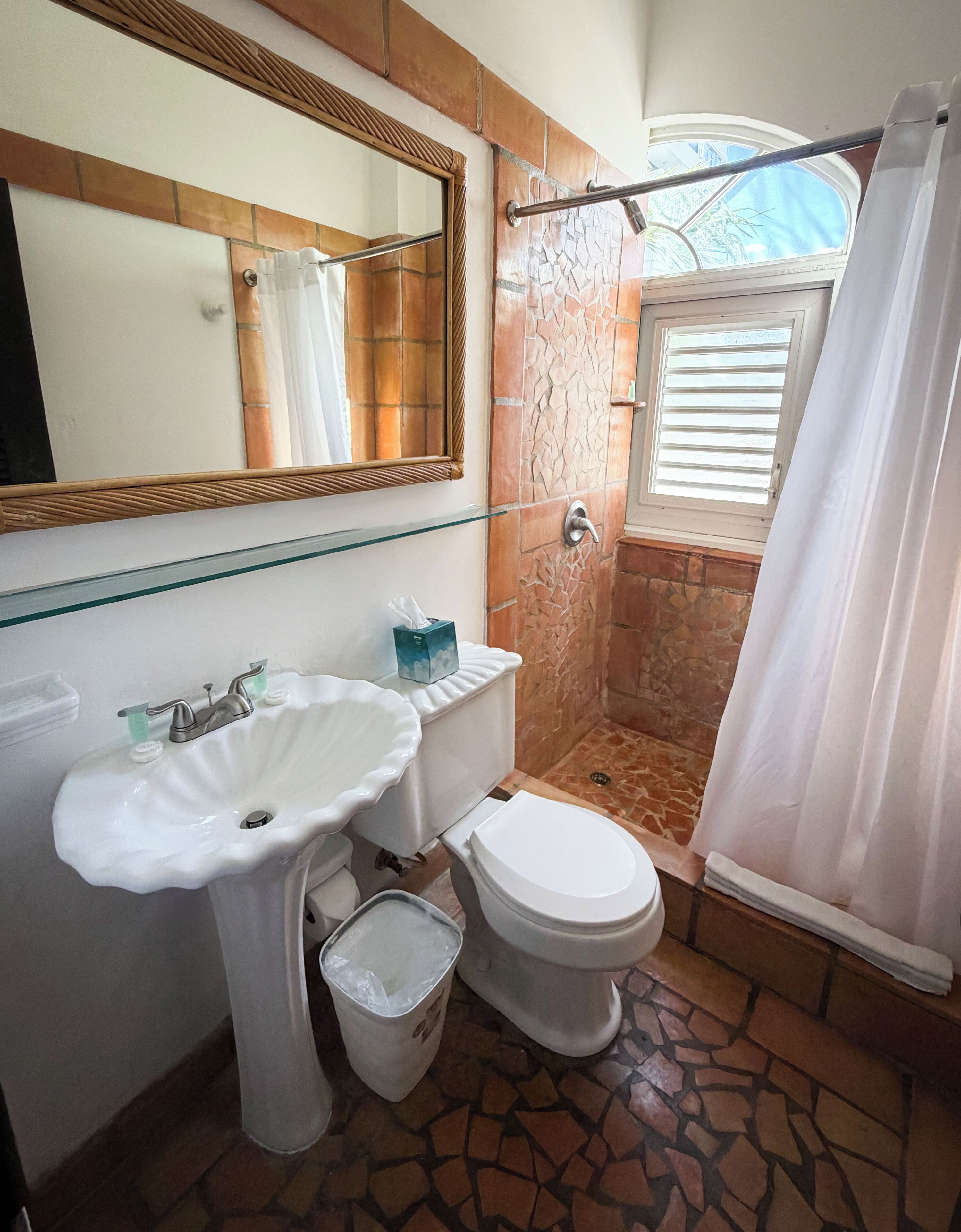 Un baño con lavamanos, inodoro y ducha blancos.