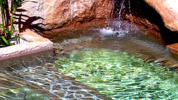Stunning water feature with a gentle waterfall and lush greenery surrounds a serene pool.