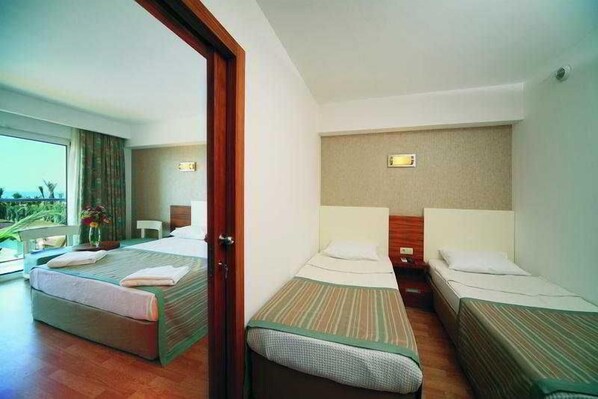 Ein Hotelzimmer mit zwei Einzelbetten, einem kleinen Tisch und Blick ins Freie.