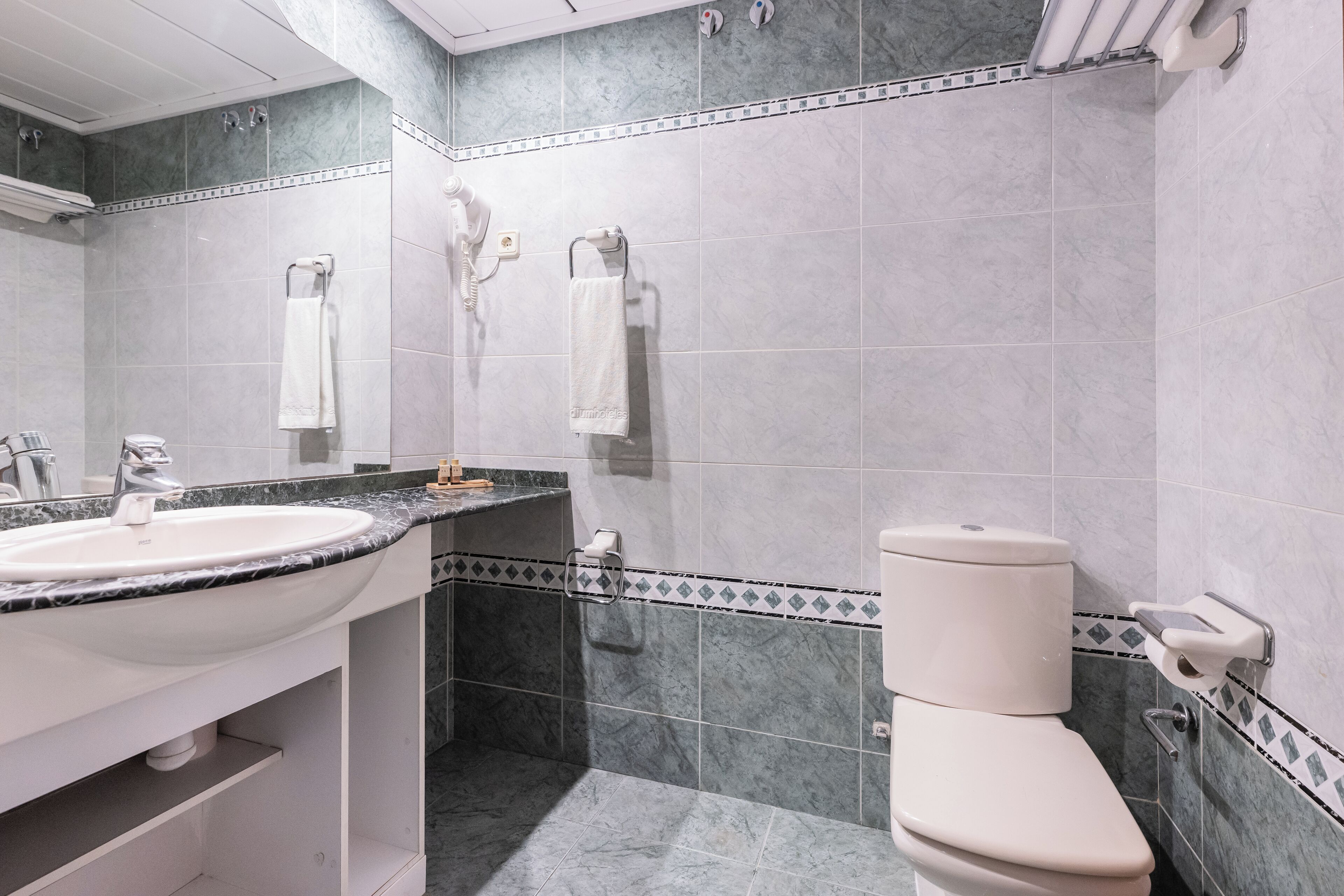 Une salle de bain équipée d’un lavabo, de toilettes et de porte-serviettes.