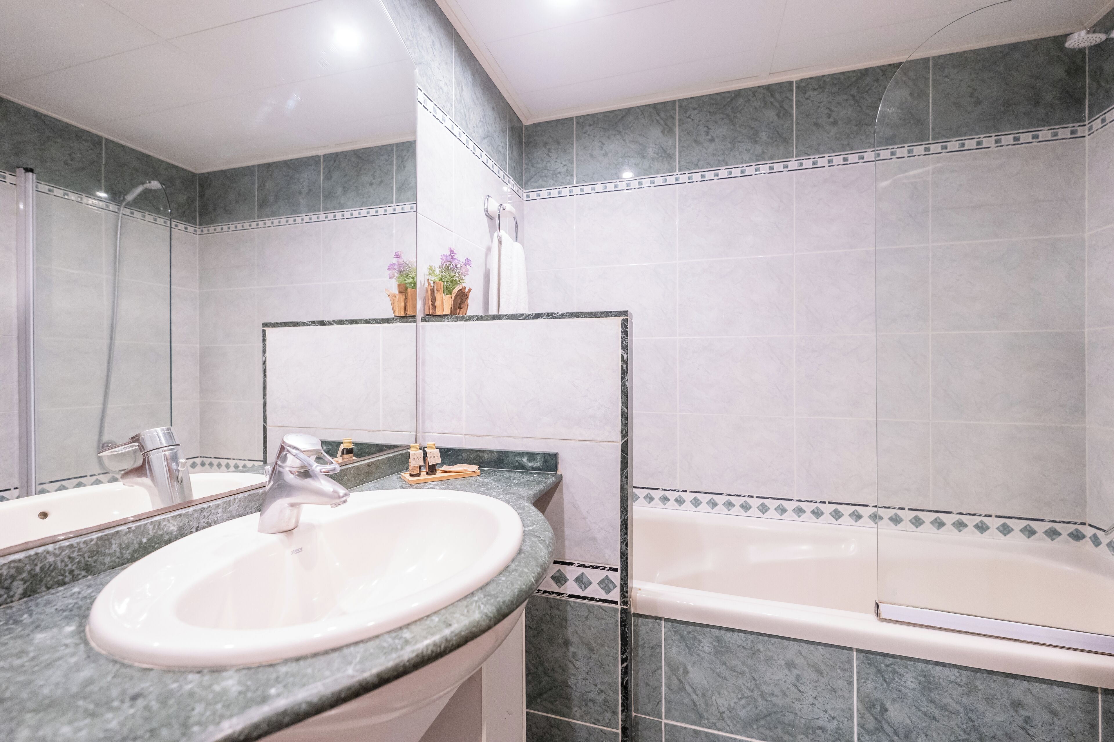 Een badkamer met een dubbele wastafel, een bad en een spiegel.