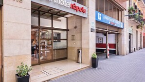 Un edificio con un cartel que dice 'Aparthotel Napoli' y un letrero de estacionamiento público.