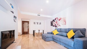 Una sala de estar moderna con un sofá seccional gris, un televisor de pantalla plana y un comedor con una mesa y sillas.