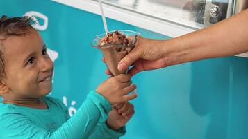A child receiving a drink from a vehicle with a turquoise exterior.