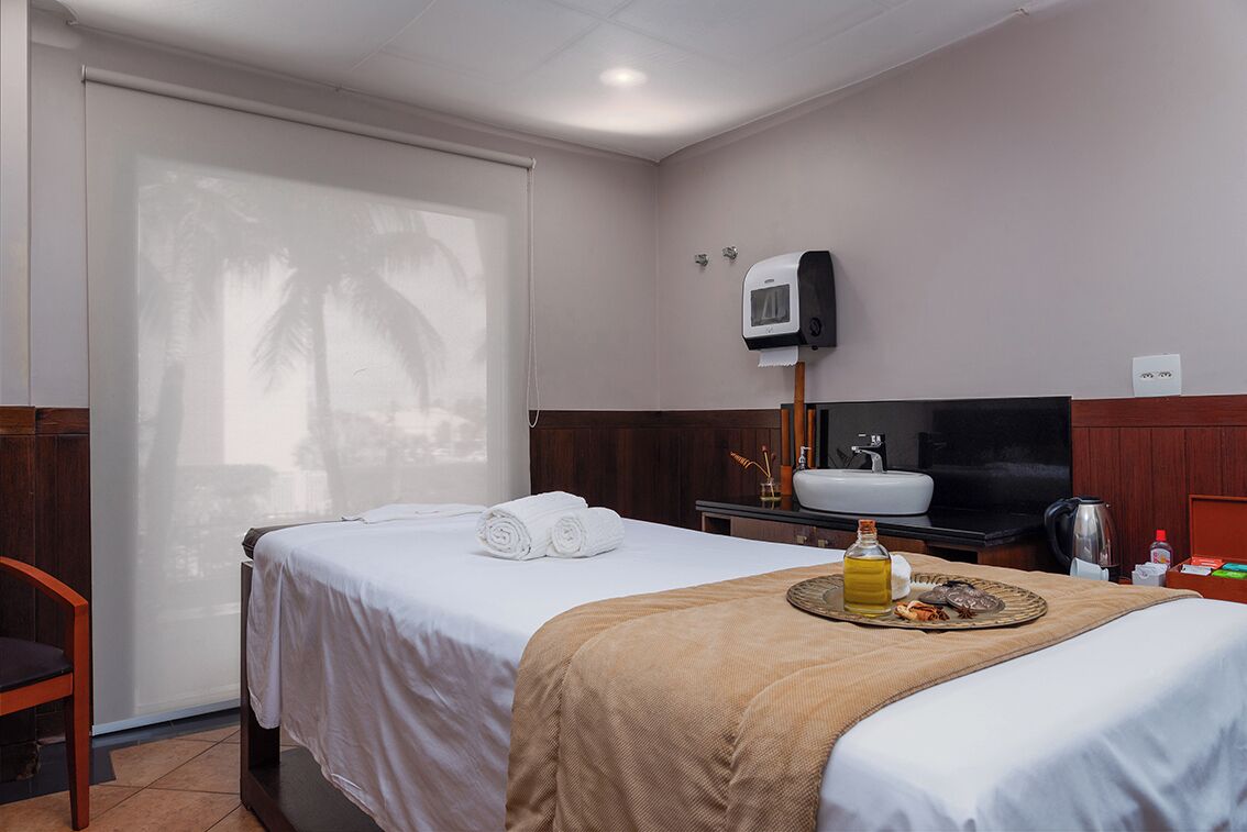 A hotel room with a bed, a TV, a sink, and a minibar.