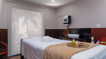 A hotel room with a bed, a TV, a sink, and a minibar.