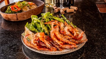 Una mesa de comedor con un plato de camarones cocidos y un bol de ensalada.