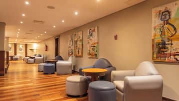 A hotel lobby with seating areas, wooden flooring, and artwork on the walls.