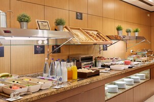 A buffet setup with various food items, beverages, and a coffee machine.