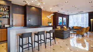 A modern bar area with a counter, stools, and a seating area with sofas and patterned chairs. - Eurostars Monumental (Barcelona)