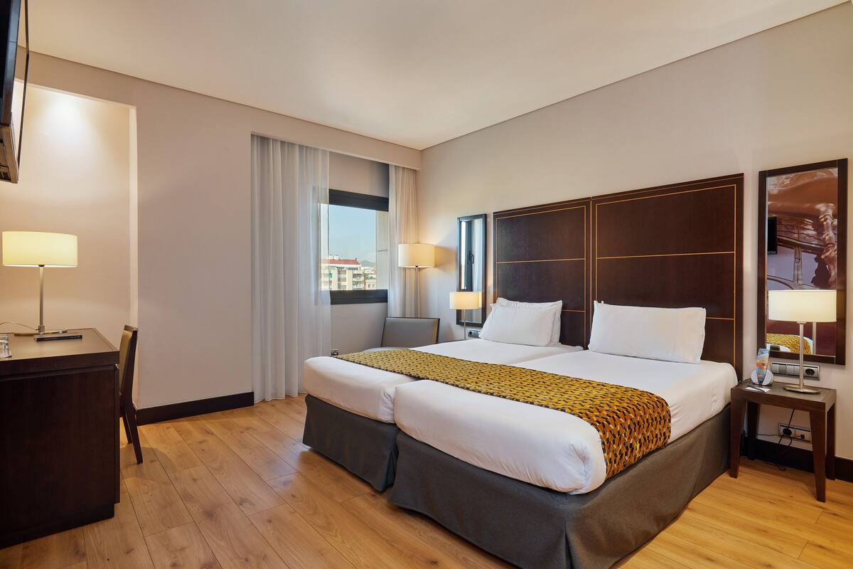Une chambre d’hôtel avec un grand lit, un bureau et une chaise.