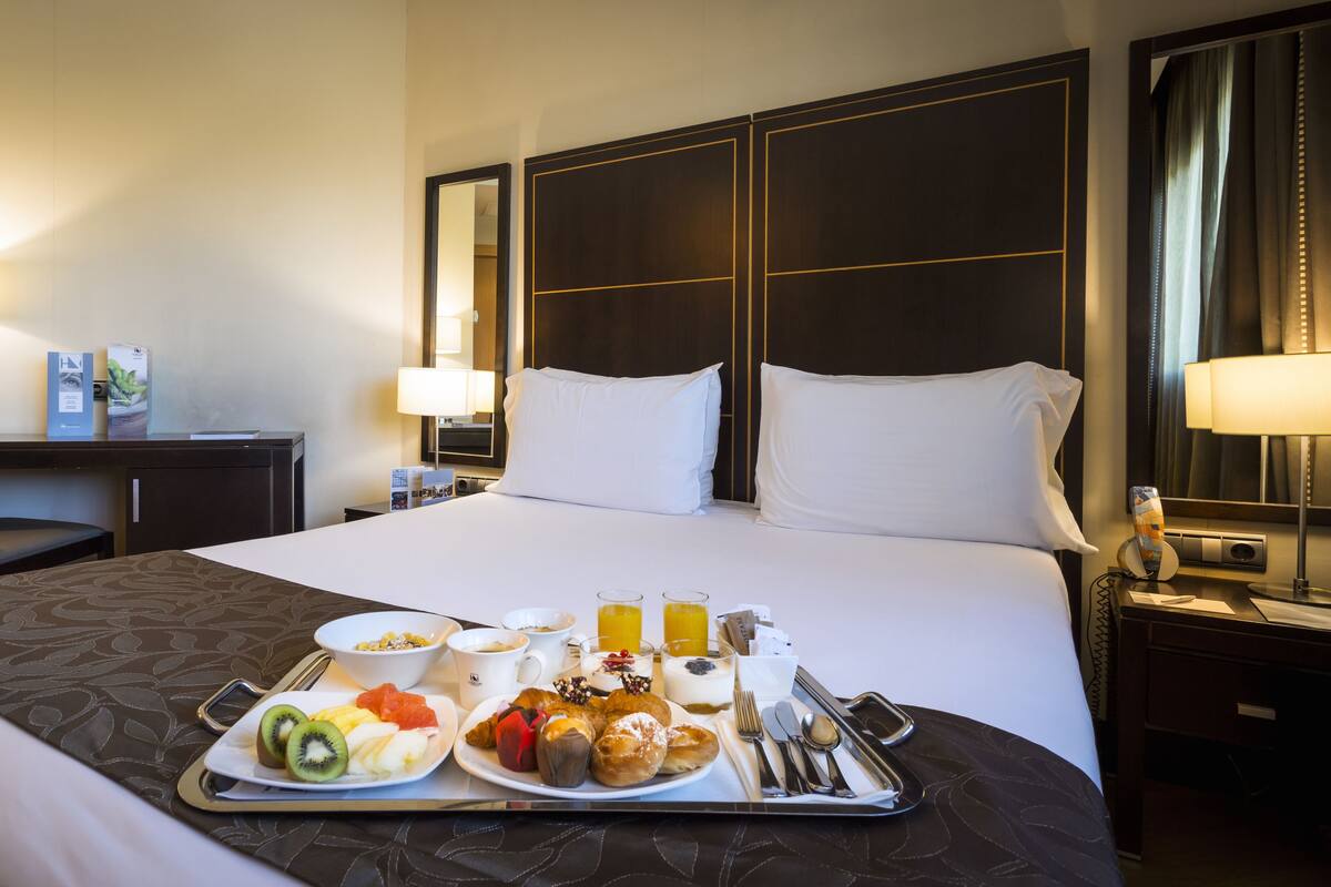 Une chambre d’hôtel avec un grand lit, un bureau et un plateau contenant des articles pour le petit-déjeuner.