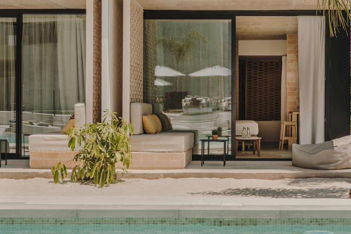 A modern outdoor pool area with a seating area, a small table, and a potted plant.