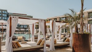 Un resort frente a la playa con bungalows sobre el agua, una piscina y palmeras.