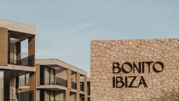 Un edificio moderno con varios balcones y una pared de piedra con el letrero "BONITO IBIZA".