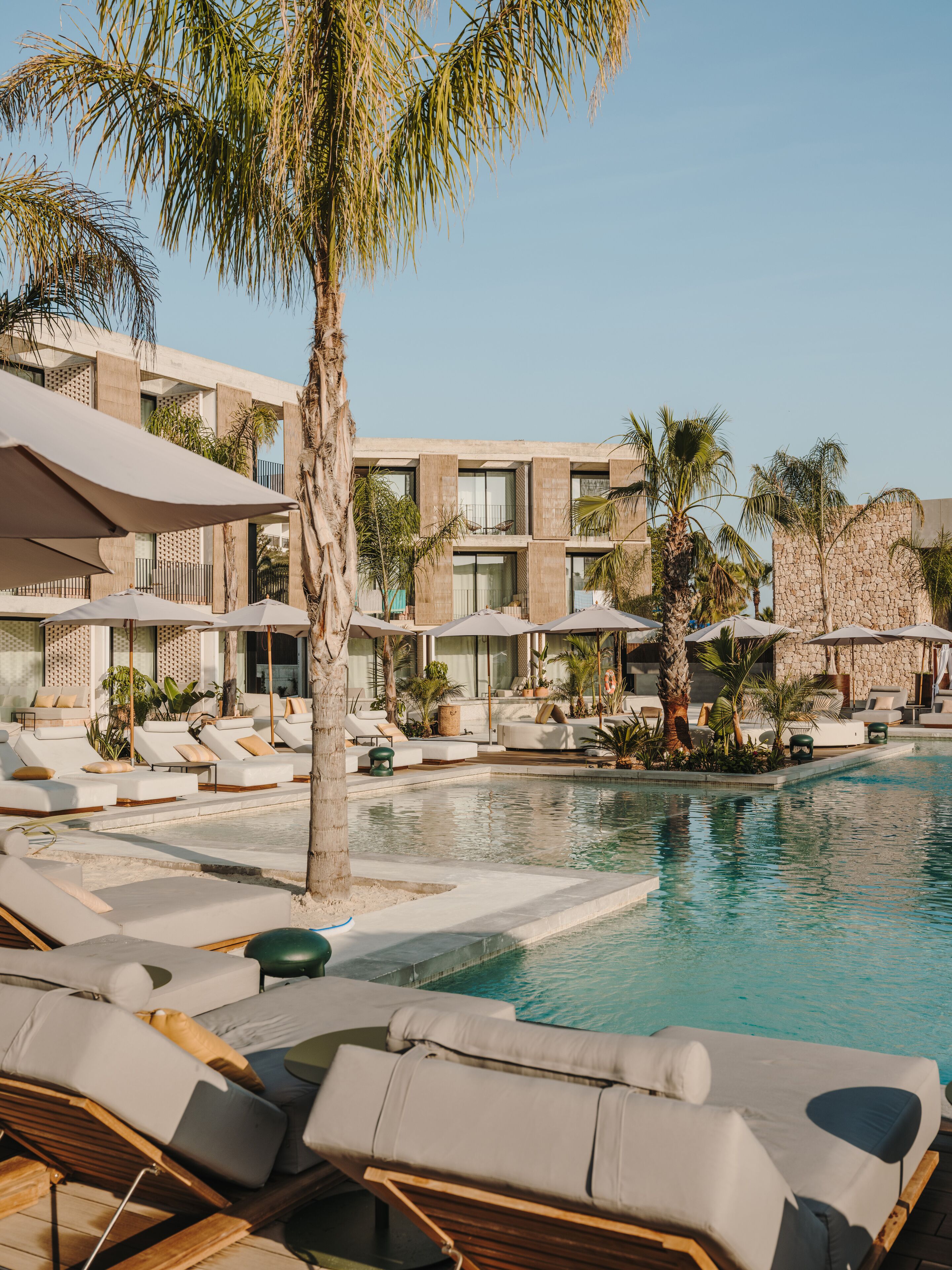 A poolside area with sun loungers, umbrellas, and a stone building.