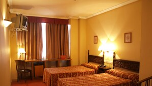 Una habitación de hotel con dos camas, un escritorio, una silla, un televisor y una lámpara.