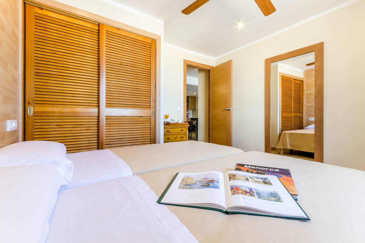 Una habitación de hotel con una cama grande, un armario de madera y un libro sobre la cama.