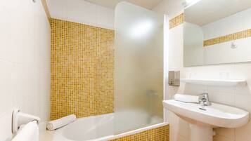 A bathroom with a bathtub, a sink, and a shower area.
