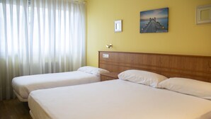 Habitación de hotel con dos camas, cabecero de madera, un cuadro en la pared y una ventana con cortinas.
