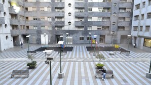 Un patio con varias bancas, un parque infantil y un edificio con balcones.