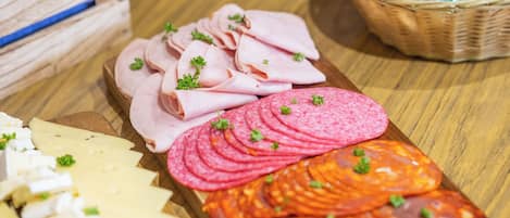 A variety of food items including sliced meats, cheeses, and packaged goods on a wooden table.