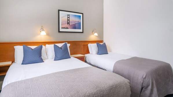 A hotel room with two beds, a wooden headboard, a framed picture of a bridge, and two wall-mounted lamps. - The Washington (Bristol)