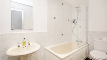 A bathroom with a sink, bathtub, toilet, and a glass-enclosed shower.