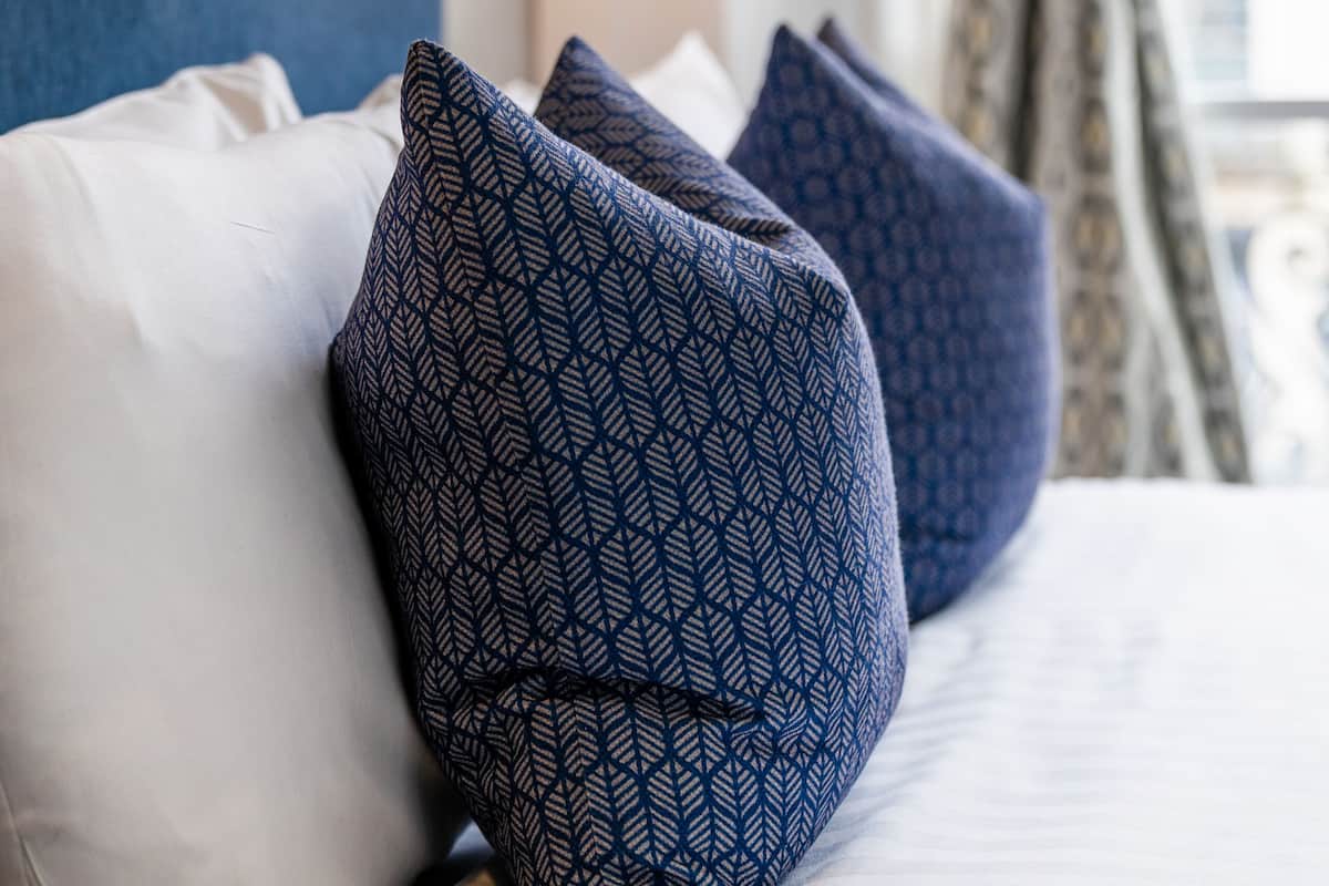 A bed with patterned pillows and a wall-mounted light fixture.
