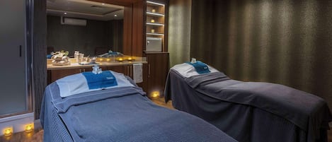 Un cuarto de spa con dos camas, un mostrador de recepción y un espejo.