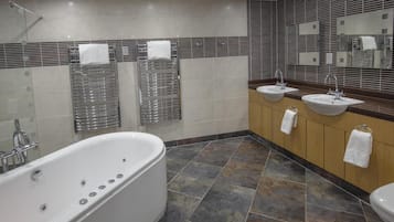 Un baño moderno con una bañera independiente, dos lavamanos y un espejo grande.