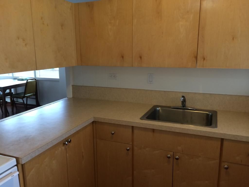 A kitchen with wooden cabinets, a stainless steel sink, and a countertop.