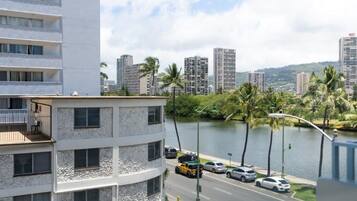 A multi-story hotel with balconies, a view of a river, and palm trees.
