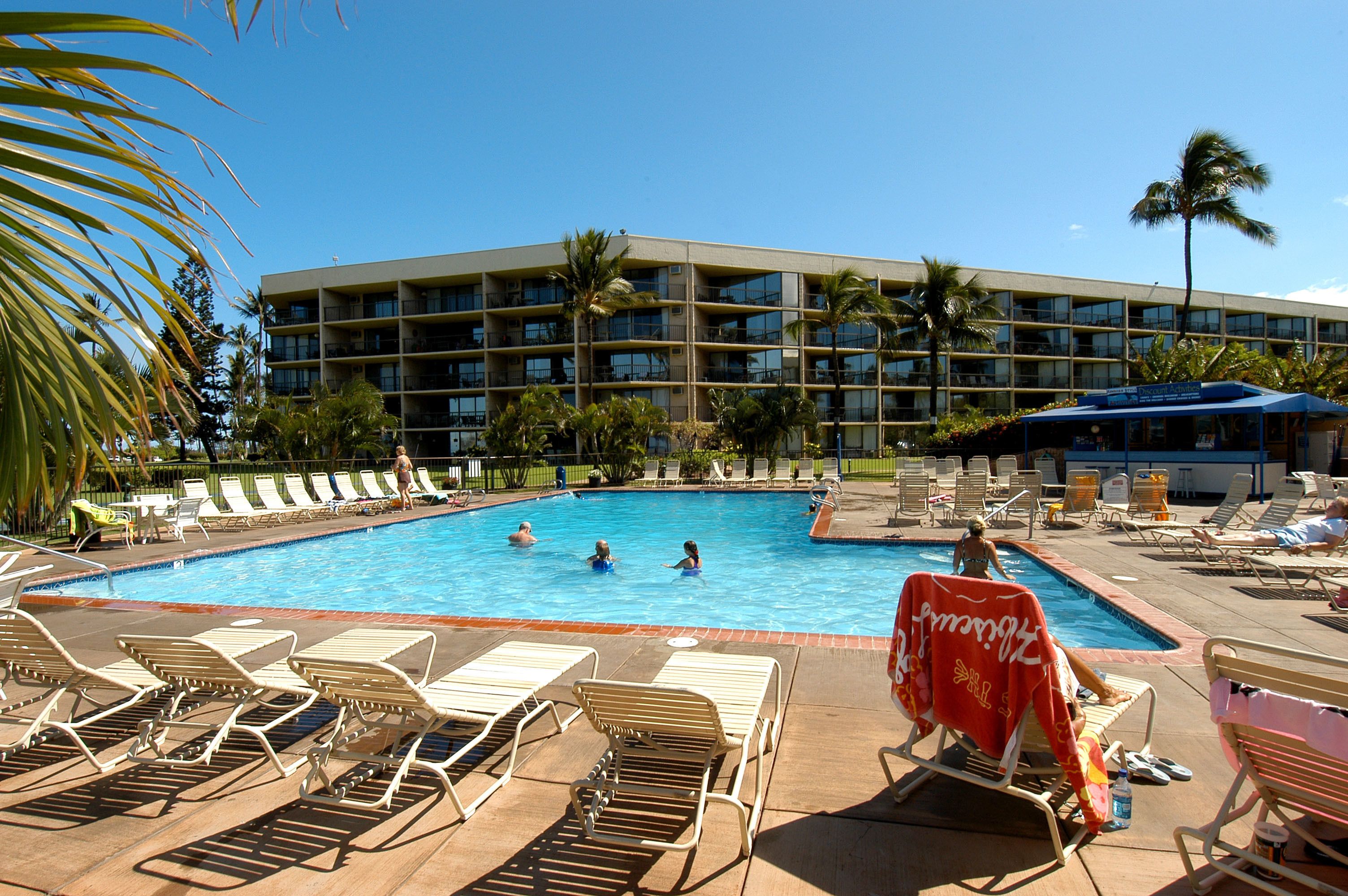 A pool area with lounge chairs and a building in the background.